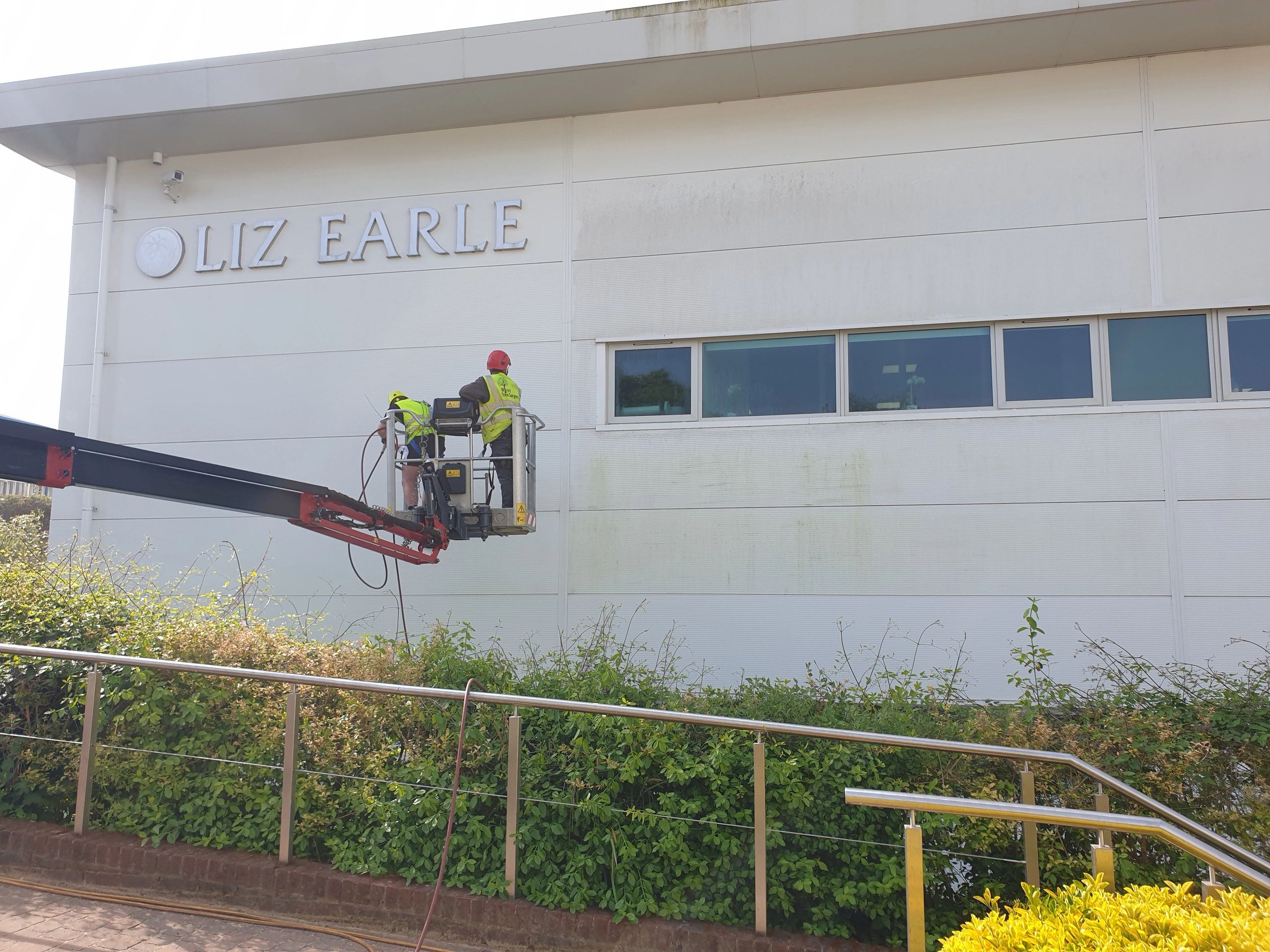 Worker on cherry picker cleaning commercial building
